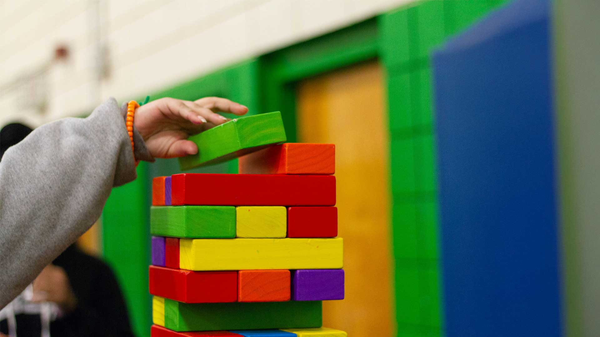 Hand of a child building a tower with colored bricks